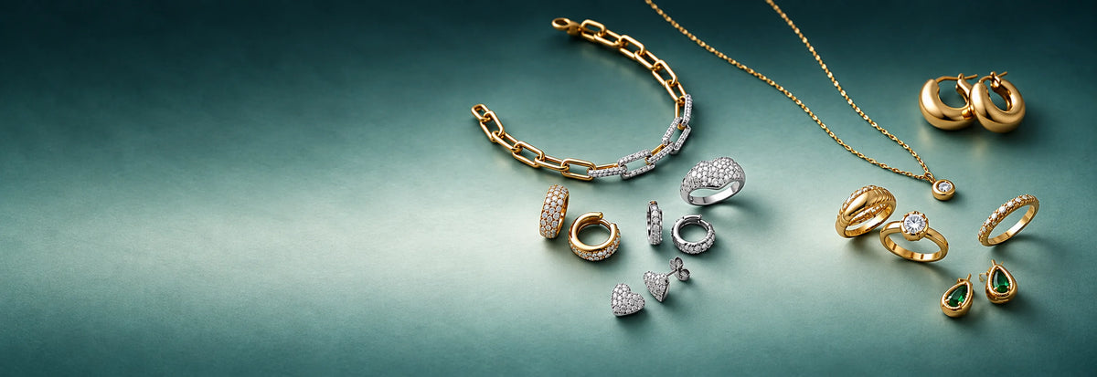 Gold bracelets, necklace, rings and earrings arranged on a teal background