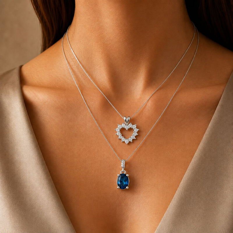 Model wearing a diamond heart pendant and a blue gemstone pendant