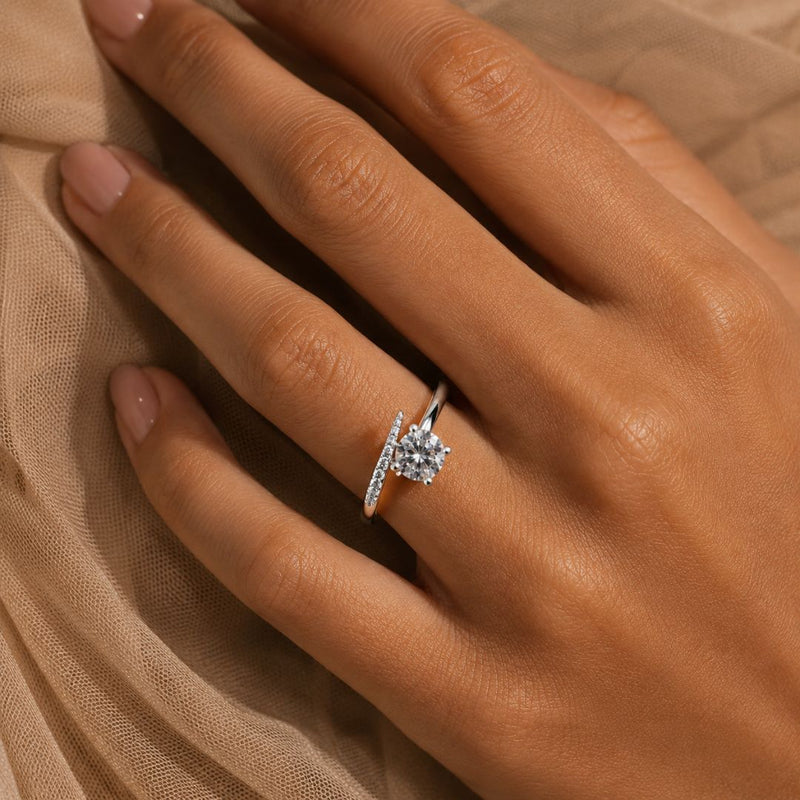 Diamond solitaire engagement ring with pavé band worn on a hand