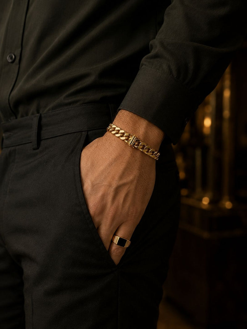 Man wearing a yellow gold Cuban link bracelet and onyx signet ring