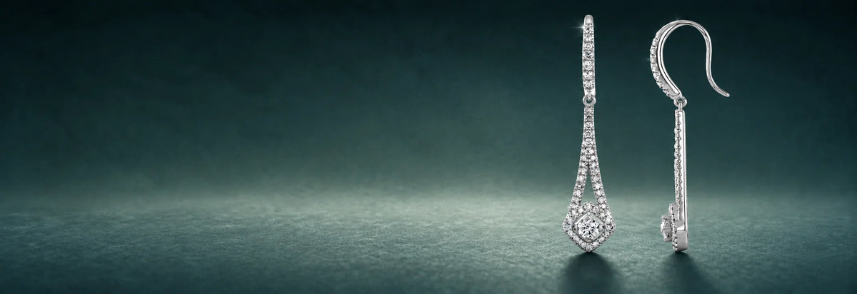 White gold diamond dangle earrings on a dark teal background